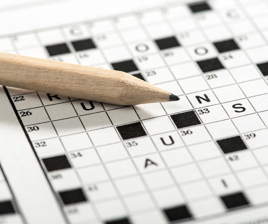 A semi-completed crossword sits on a table with a pencil on top