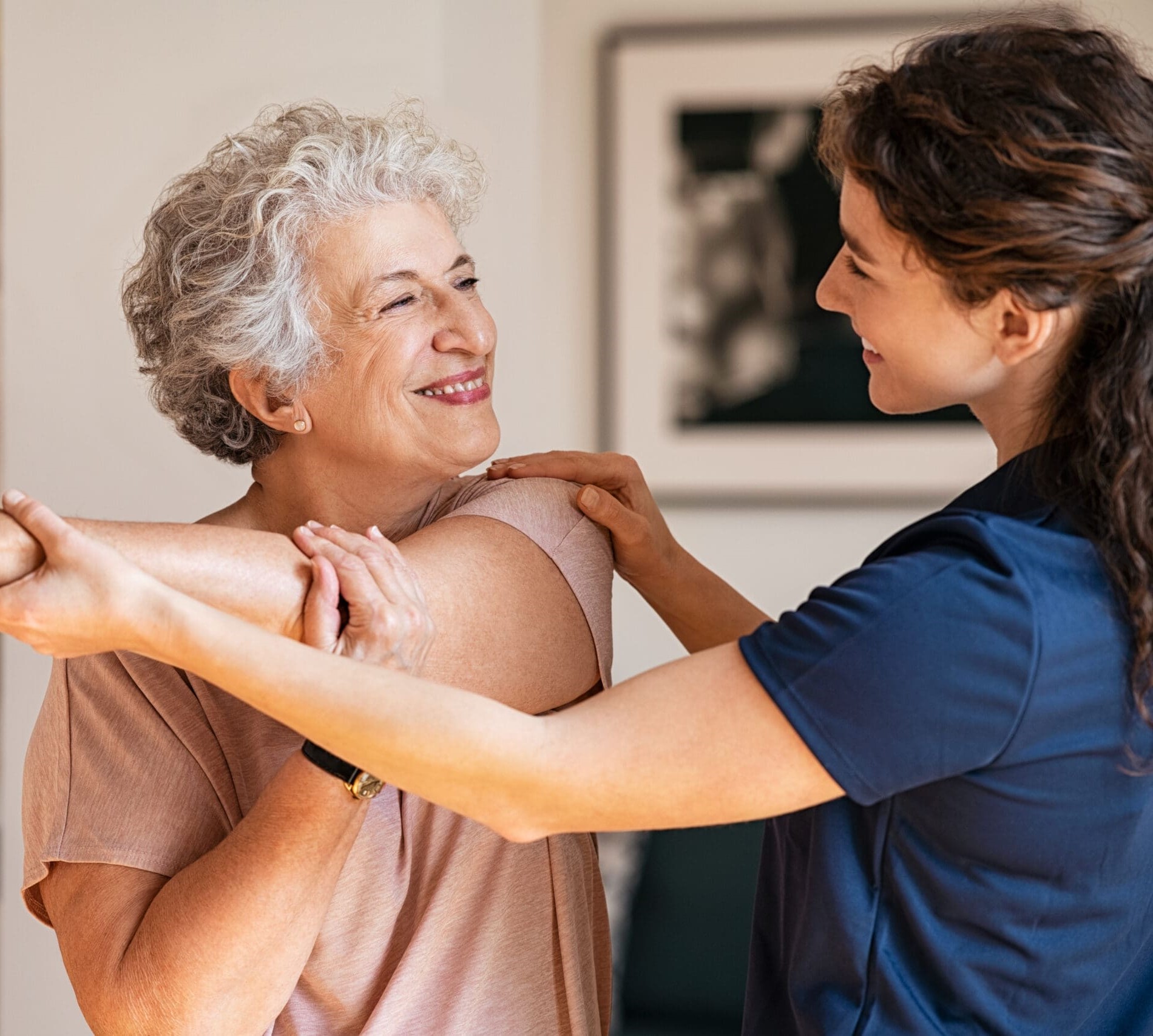 A carer helps an older woman with physio and stretches