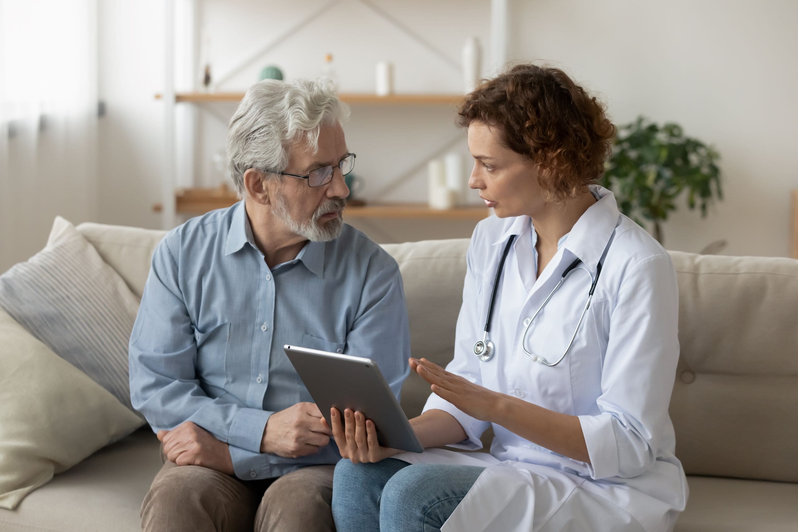 A doctor and man are discussing care plans on a digital tablet