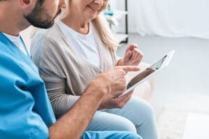 Two carers look at an electronic tablet together