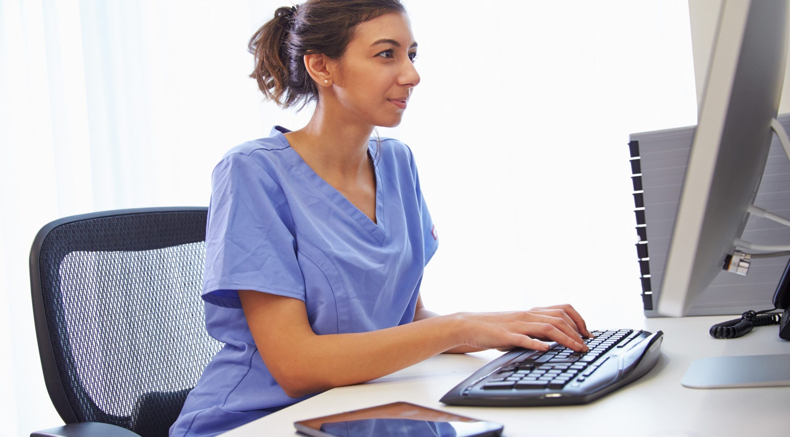 A carer looks at her desktop computer intently