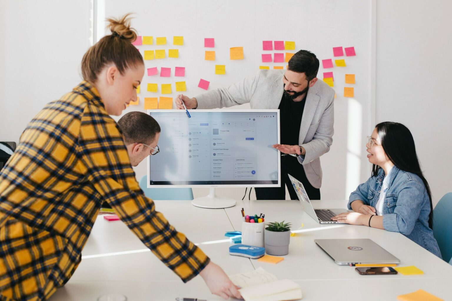 A group organise their thoughts in a meeting with post-it notes on a board