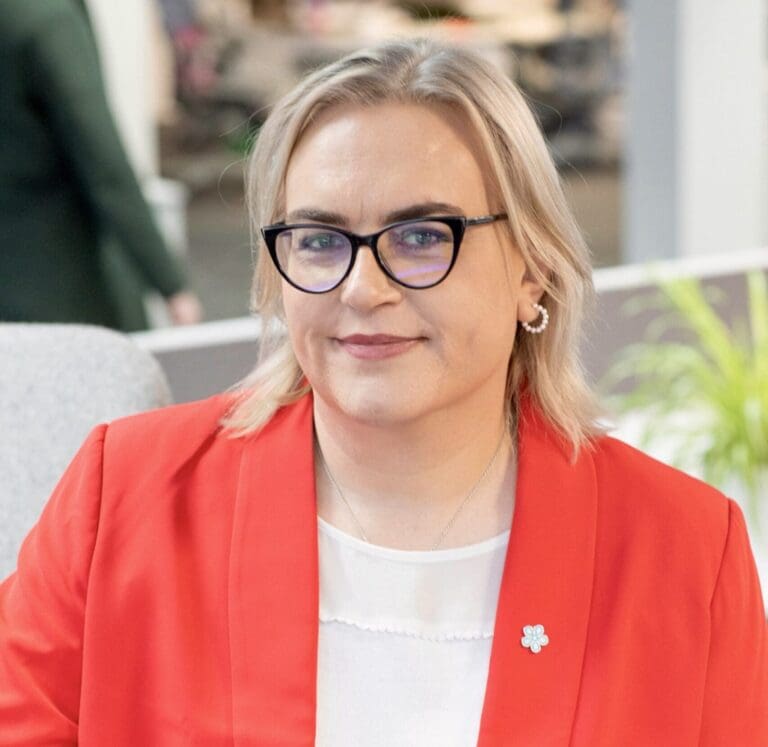 Nourish CMO Lee Gilbert smiles for the camera in her red blazer