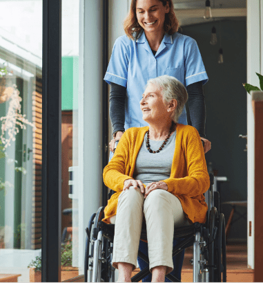 A nurse helps guide a silver-haired woman in a wheelchair
