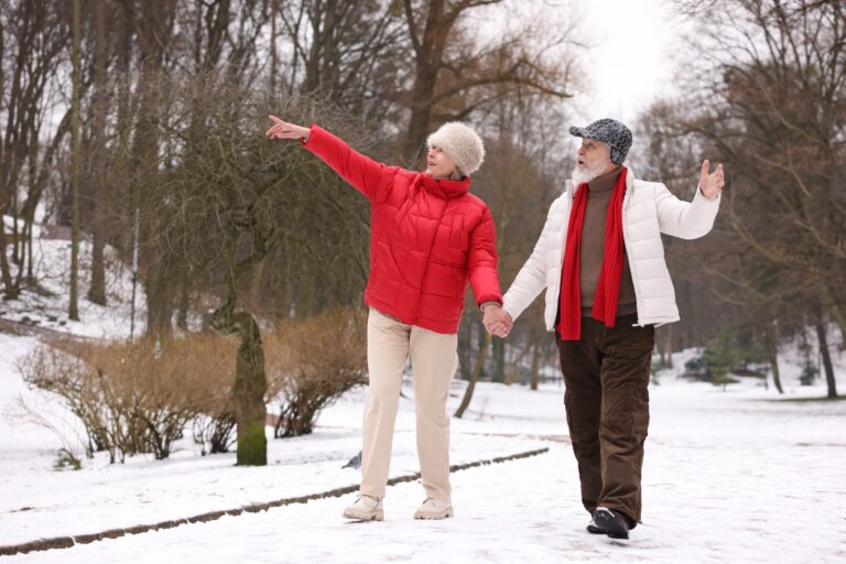 Happy older couple walking in winter park.