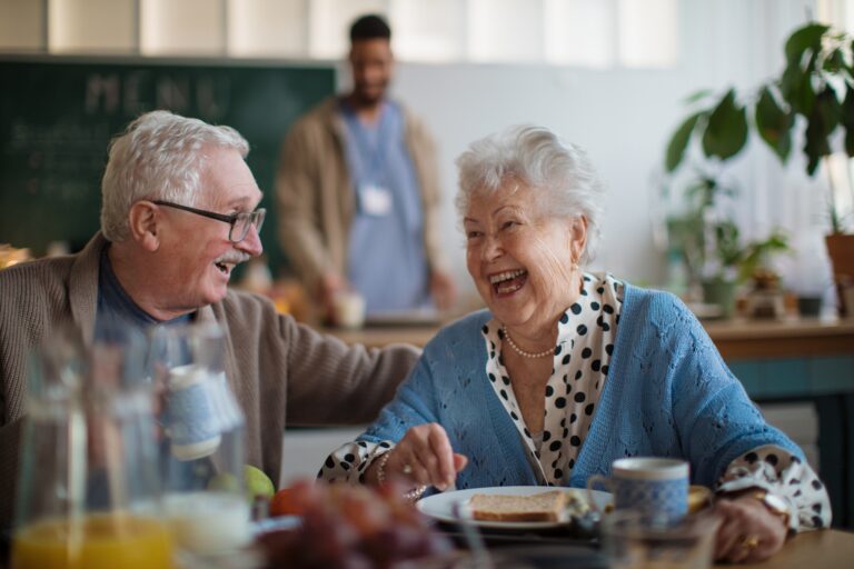 An older couple share a joke together at the dinner table